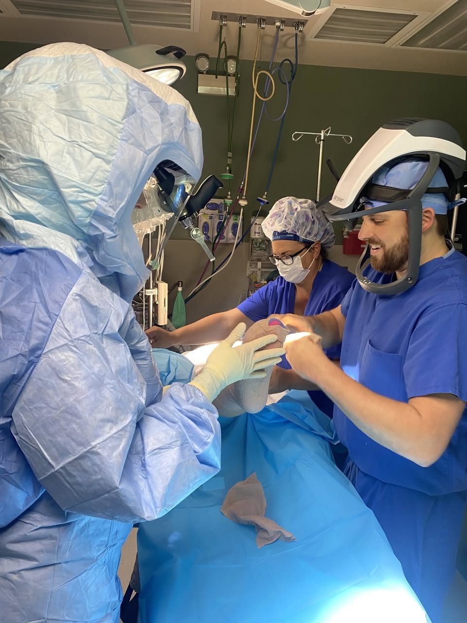 Dr. MacNeille and his operating room team applying a soft compression dressing to a patient's knee at the end of a knee replacement.